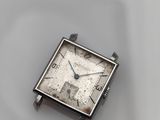 a small square watch sitting on top of a white plate