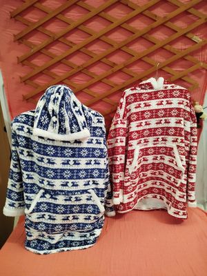 two sweaters sitting on top of a bed next to each other