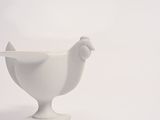 a white bowl with a spoon in it on a white surface