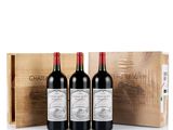 three bottles of red wine in a wooden box on a white surface