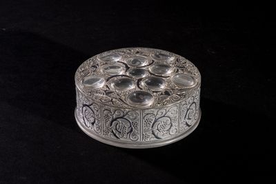 an ornate silver box with a flower design on it on a black surface