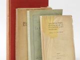 several old books are stacked on top of each other on a white surface