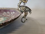 a silver plate with a bird on it on a table