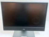 the dell monitor is sitting on a stand on a white surface