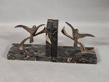 two birds that are standing on a marble bookend