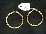 deux boucles d'oreilles en anneau dorées avec une étiquette de prix sur fond noir