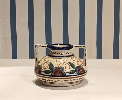 a blue and white vase on a table with a striped wall behind it