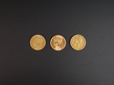 trois pièces d'or posées sur une surface noire
