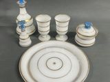une assiette blanche ornée d'une fleur bleue, à côté d'un service de tasses et de soucoupes