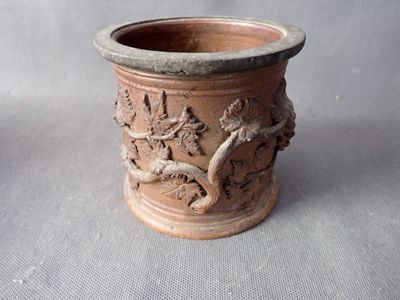 a brown vase with a bird on it on a table