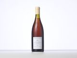 a bottle of wine sitting on top of a table next to a white wall