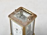 a small brass clock with a glass face on a white surface