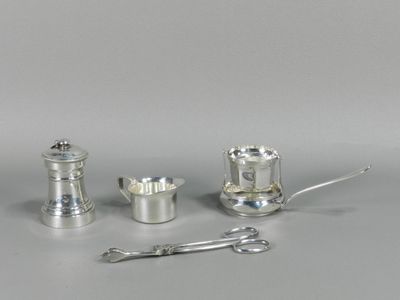 trois objets en argent posés sur une table, avec une cuillère et un repose-cuillère