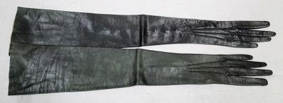 une paire de gants en cuir noir posée sur une table blanche