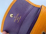 someone is holding a purple and orange purse with a gold clasp