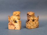 two carved figurines of dogs on a wooden block