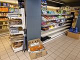 Des cartons de produits alimentaires sont empilés par terre dans une épicerie