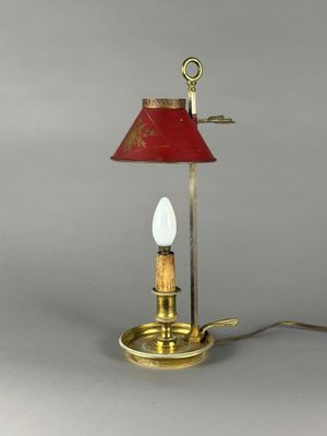 une lampe de table en laiton surmontée d'un abat-jour rouge