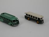 two toy buses sitting next to each other on a white surface