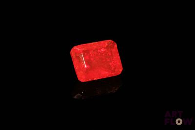 a red diamond on a black surface with a black background