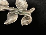 a silver flower brooch on a black background