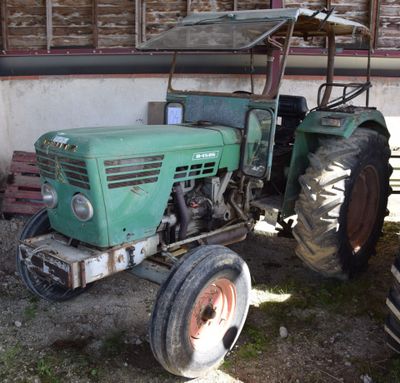 a green tractor parked in front of a building
