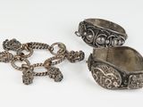 two pieces of silver jewelry on a white surface