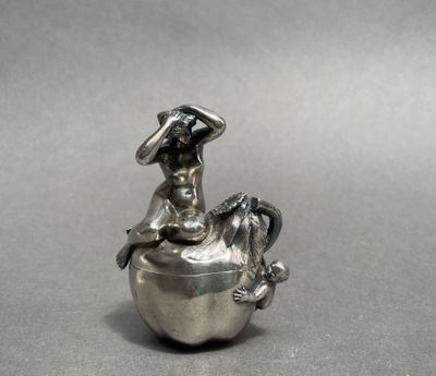 une figurine en argent représentant une femme assise sur une pomme