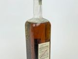 an old bottle of whiskey sitting on top of a white surface