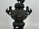 une image représentant un vase en bronze surmonté d'un oiseau