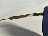 sunglasses with a gold frame and blue lenses on a white surface