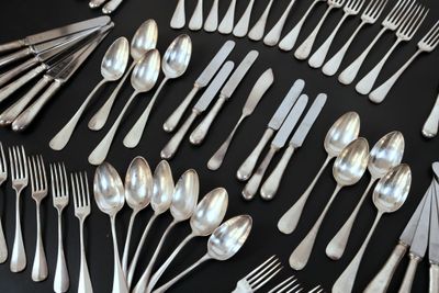 un grand nombre de cuillères et de fourchettes disposées sur une table
