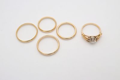 cinq bagues en or et une bague en diamant posées sur un fond blanc