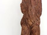 une statue en bois représentant un homme tenant un chien, posée sur un socle