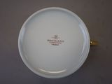 a white plate with a gold handle on a table