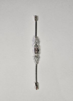 un bracelet en argent orné d'une clé, posé sur un fond blanc