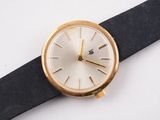 a gold watch on a black strap on a white surface