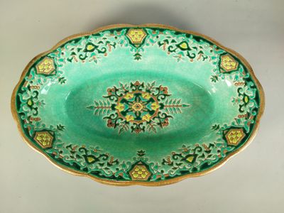 une image représentant une assiette verte et dorée ornée d'un motif floral