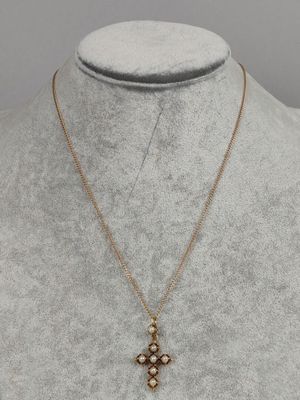 a gold necklace with a cross pendant on a mannequin mannequin