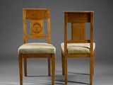 two wooden chairs with upholstered seats and a clock on the back of the chair