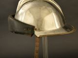 a silver helmet on a stand with a leather strap
