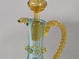 a blue glass bottle with a gold handle on a white surface
