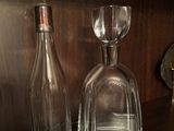 une bouteille et un verre posés sur une étagère à côté d'une horloge