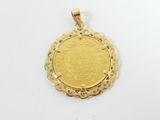 a gold coin pendant with an ornate design on a white background