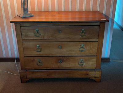 une commode en bois sur laquelle est posée une lampe