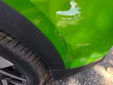 a close up of a green car that is parked on the street