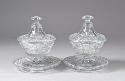 une paire de sucriers et poivriers en cristal taillé, posés sur leurs soucoupes