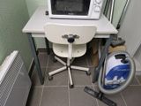 une petite table sur laquelle se trouvent un micro-ondes et un aspirateur