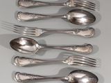 six cuillères en argent et une fourchette sont alignées sur une table