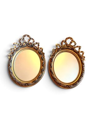 une paire de miroirs à cadre doré sur fond blanc